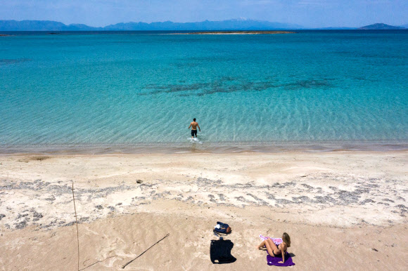 한 커플이 23일(현지시간) 그리스 남부의 작은 섬인 엘라피니소스의 해변에서 바다를 즐기고 있다. AFP 연합뉴스