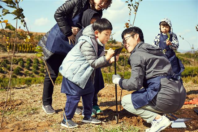 한화그룹 ‘태양의 숲’ 조성 행사에 참여한 ‘태양의 숲 원정대’가 묘목을 심은 뒤 메시지를 남기고 있다. 한화그룹 제공