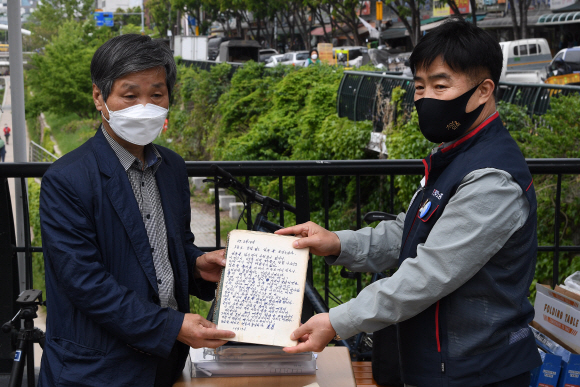 전태일 일기장 관리위원회 회원들이 29일 서울 청계천 전태일 열사 동상 앞에서 전태일 일기장 육필 원본 공개 기자회견을 열고 있다. 전태일 열사의 동생 전태삼 씨(왼쪽)가 열사의 육필 일기장을 공개하고 있다. 2021.4.29 오장환 기자 5zzang@seoul.co.kr