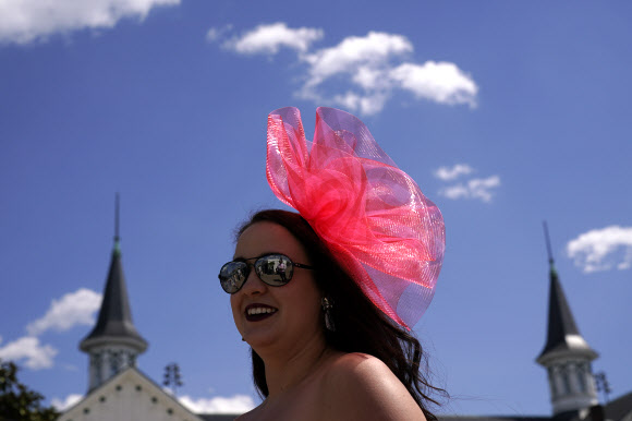 30일(현지시간) 미국 켄터키주 루이빌 처칠다운 경마장에서 유명 경마대회 ‘컨터키 더비’가 열린 가운데 화려한 의상과 독특한 모자를 쓴 관람객이 마스크를 착용하지 않은채 관람하고 있다. AP 연합뉴스