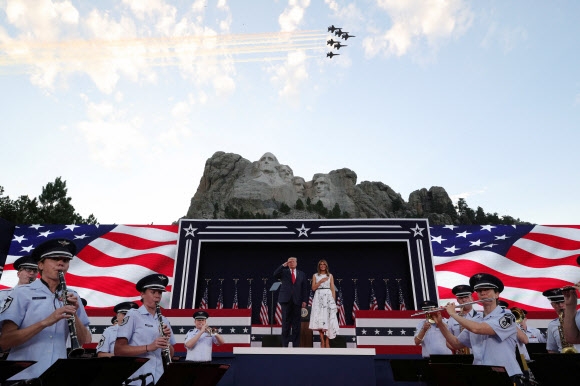 도널드 트럼프 미국 대통령이 지난해 7월 3일(현지시간) 사우스다코타주 러시모어산 앞에서 거수 경례를 하는 가운데 전투기 편대가 축하 비행을 하고 있다. 키스톤 로이터 연합뉴스