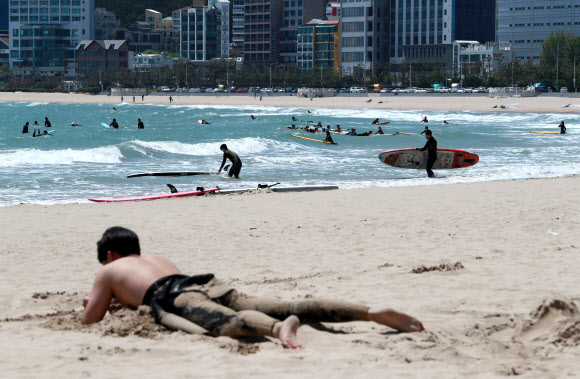 초여름 날씨를 보인 3일 오후 부산 해운대구 송정해수욕장에서 한 서퍼가 모래찜질을 하고 있다. 2021.5.3  연합뉴스