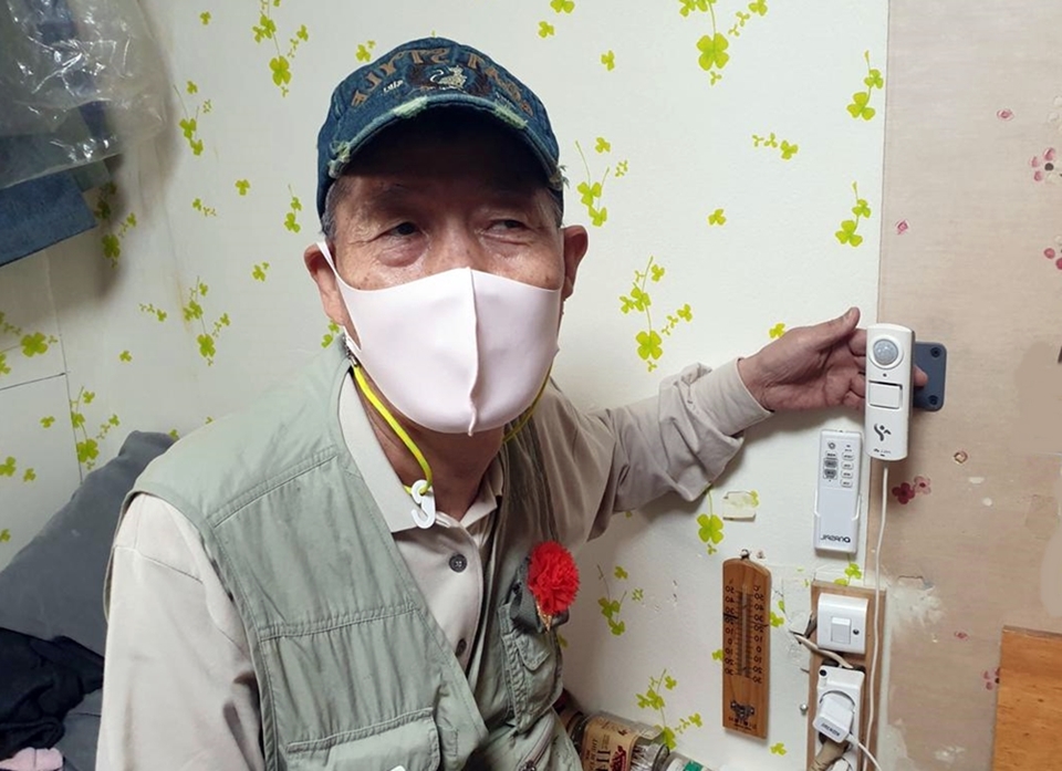 서울 성북구에서 홀로 거주하는 한 어르신이 자신의 집에 설치된 안전건강관리 사물인터넷(IoT) 기기를 가리키고 있다. 성북구 제공 