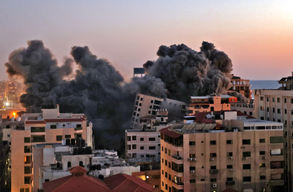 이스라엘군이 11일(현지시간) 무장 정파 하마스가 통치하는 팔레스타인 가자시티 하나디 일대에 공습을 단행해 건물이 폭파되면서 검은 연기를 내뿜고 있다. 2014년 이후 7년 만에 이스라엘군과 하마스 간의 공격과 보복 반격이 되풀이되는 대규모 무력 충돌로 ‘피의 악순환’에 빠져들고 있다. 가자시티 AFP 연합뉴스