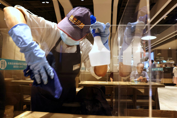 타이완의 한 식당 직원이 코로나 방역을 위해 플라스틱 가림막을 닦고 있다. 연합뉴스 