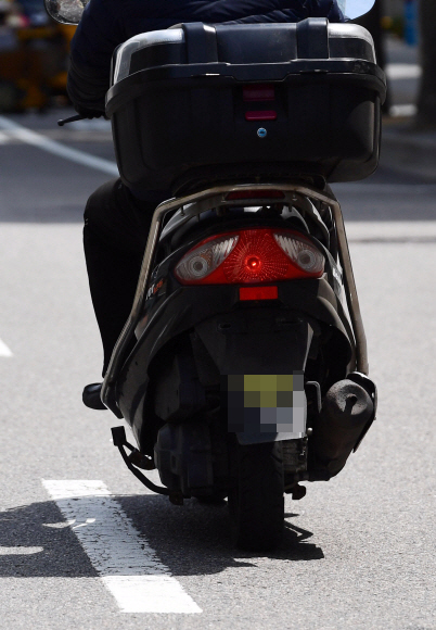 한 배달 오토바이가 번호판을 제거한 채 도로를 주행하고 있다.