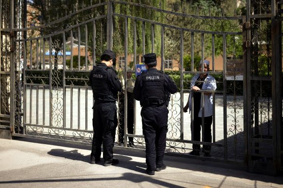 두 명의 중국 공안이 6일 중국 신장 위구르 자치구의 이슬람 사원 방문을 요구하고 있다. 연합뉴스