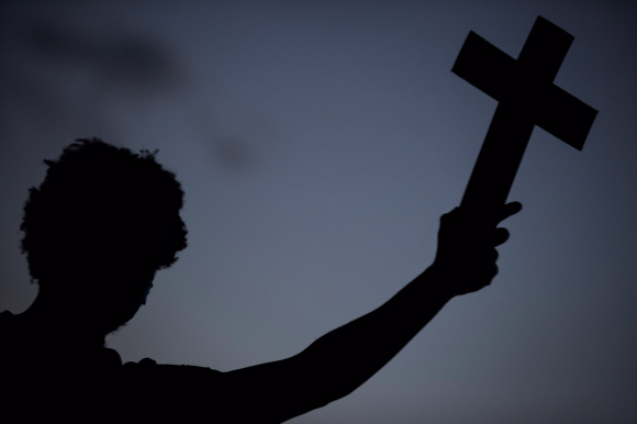 반정부집회 참가자가  13일 리오데자네이로에서 열린 브라질 노예제도 폐지 133주년을 기념하는 인종차별 반대 집회에서 십자가를 들고  인종차별과 경찰 폭력에 항의하고 있다. 사진=EPA 연합뉴스