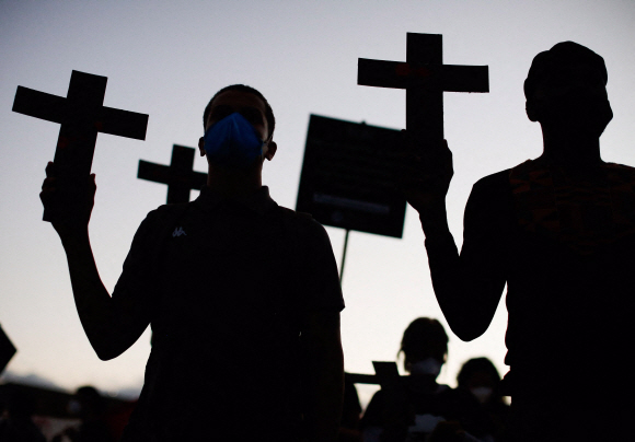 흑인 운동가들이  13일 브라질리아에서 열린 브라질 노예제도 폐지 133주년을 기념하는 인종차별 반대 집회에서 십자가를 들고  인종차별과 경찰 폭력에 항의하고 있다. 사진=AFP 연합뉴스