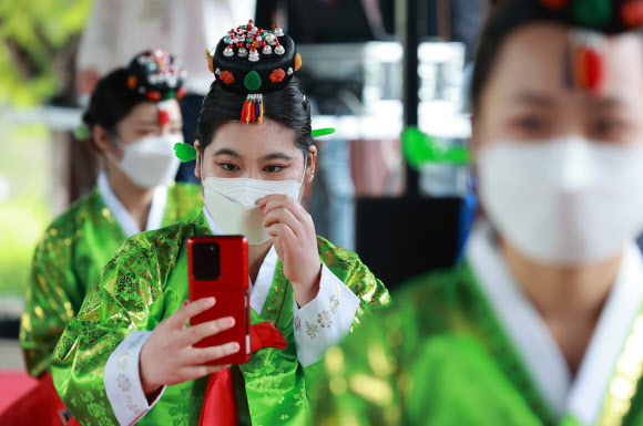 성년의 날인 17일 오전 서울 중구 남산골 한옥마을에서 열린 제49회 전통 성년례 재현행사에서 한 참석자가 행사를 마친 뒤 휴대전화로 기념사진을 찍고 있다. 2021.5.17  연합뉴스