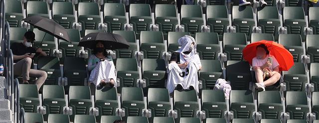 이른 더위가 찾아온 19일 서울 잠실야구장을 찾은 관람객들이 응원도구와 우산을 이용해 태양을 피하고 있다. 2021.5.19 뉴스1