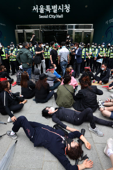 20일 오후 한국유흥음식업중앙회·한국단란주점업중앙회·한국콜라텍협회 관계자 및 업주들이 정부에 집합금지 해제 및 손실보상법 통과를 촉구하며 서울 중구 서울시청 내부로 진입하던 중 경찰에 막혀 자리에 앉아 있다. 2021.5.20  연합뉴스