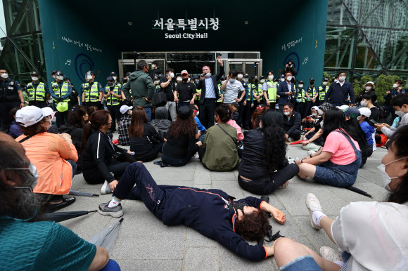 20일 오후 한국유흥음식업중앙회·한국단란주점업중앙회·한국콜라텍협회 관계자 및 업주들이 정부에 집합금지 해제 및 손실보상법 통과를 촉구하며 서울 중구 서울시청 내부로 진입하던 중 경찰에 막혀 자리에 앉아 있다. 2021.5.20  연합뉴스