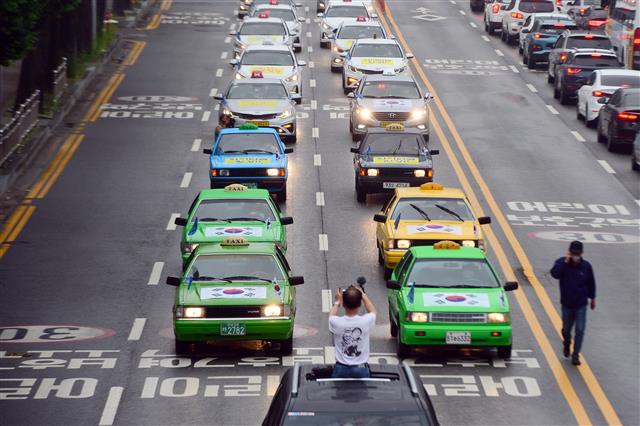 ‘제41주년 5·18민중항쟁 민주기사의 날’을 맞은 20일 오후 광주 북구 유동사거리 일대에서 태극기를 단 70여대의 민주택시노동조합 관계자들의 택시가 차량행렬 시위를 하고 있다. 민주택시노동조합은 1980년 5·18민주화운동 당시 시민군의 옛 전남도청 탈환의 기폭제가 됐던 택시 기사들의 차량행렬 시위가 있었던 5월20일을 민주기사의 날로 정하고 1997년부터 매년 이날 차량행렬 시위를 재현해 왔다. 2021.5.20 뉴스1