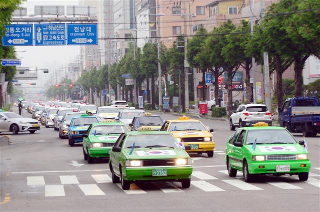 ‘제41주년 5·18민중항쟁 민주기사의 날’을 맞은 20일 오후 광주 북구 신안사거리 일대에서 태극기를 단 70여대의 민주택시노동조합 관계자들의 택시가 차량행렬 시위를 하고 있다. 민주택시노동조합은 1980년 5·18민주화운동 당시 시민군의 옛 전남도청 탈환의 기폭제가 됐던 택시 기사들의 차량행렬 시위가 있었던 5월20일을 민주기사의 날로 정하고 1997년부터 매년 이날 차량행렬 시위를 재현해 왔다. 2021.5.20 뉴스1