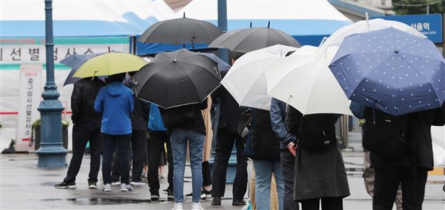 21일 서울 중구 서울역광장에 마련된 신종 코로나바이러스 감염증(코로나19) 임시 선별검사소에서 우산을 쓴 시민들이 검사를 기다리고 있다. 2021.5.21 뉴스1