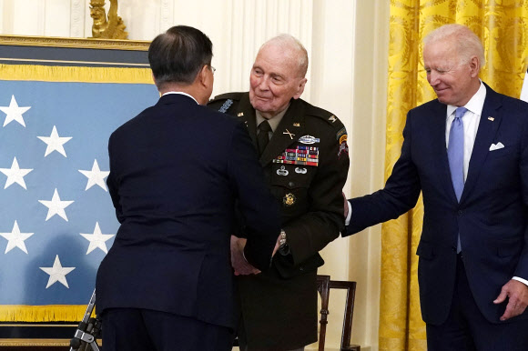문재인 대통령이 백악관에서 열린 한국전 영웅 명예훈장 수여식에 참석해 랠프 퍼켓 주니어(94) 전 대령과 악수를 나누고 있다. 오른쪽은 조 바이든 미국 대통령. AP
