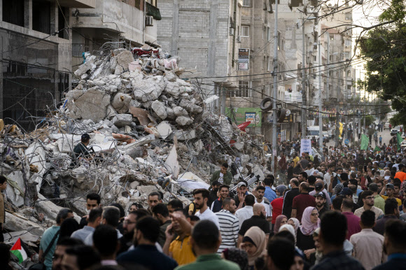 파괴된 가자지구 건물 잔해더미 옆 지나는 팔레스타인 주민들