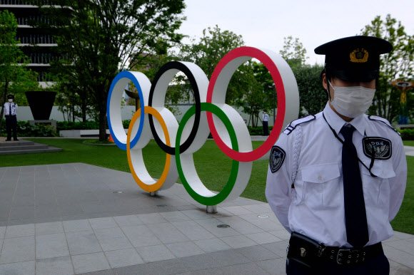 일본 도쿄의 일본올림픽위원회(JOC) 앞에 있는 올림픽 오륜기 조형물 인근에 경비 직원이 근무를 서고 있다. 2021.5.25  AFP 연합뉴스