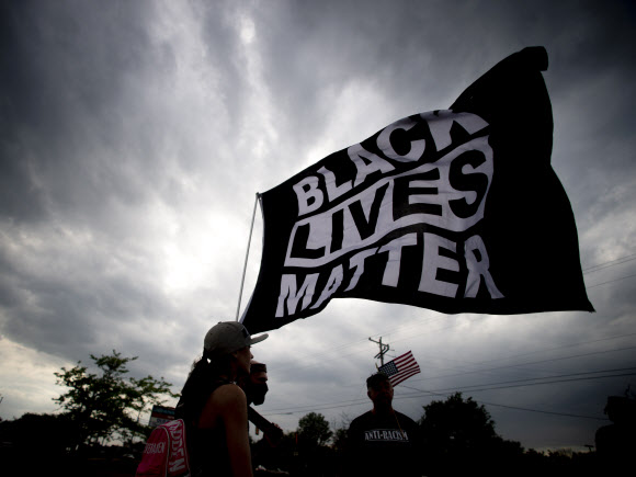 25일(현지시간) 미국 미시간주 플린트에서 조지 플로이드의 죽음을 추모하며 시위대가 ‘흑인 목숨도 소중하다’(Black Lives Matter)라고 쓰인 깃발을 흔들고 있다. 플린트 AP 연합뉴스
