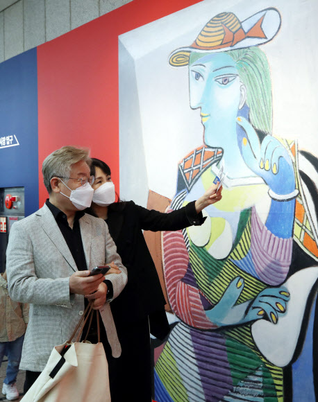 이재명 경기도지사 부부가 29일 오후 서울 서초구 예술의전당에서 열린 ‘피카소 탄생 140주년 특별전’ 관람을 위해 줄을 서 입장을 기다리던 중 사진을 찍고 있다. 2021.5.29  연합뉴스