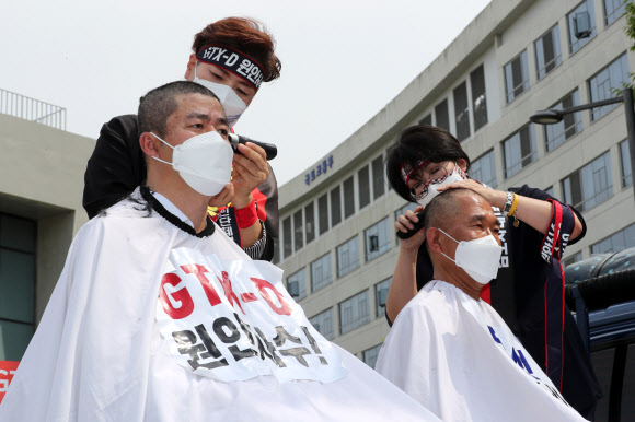 더불어민주당 김포시(갑) 김주영 의원과 김포시(을) 박상혁 의원 등 지역 공직자들이 2일 오후 세종시 정부세종청사 국토교통부 앞에서 ‘GTX-D 원안사수!’ 김포-하남 노선 반영과 서울 5호선 김포 연장을 촉구하는 집회를 열고 삭발식을 하고 있다. 2021.6.2  연합뉴스