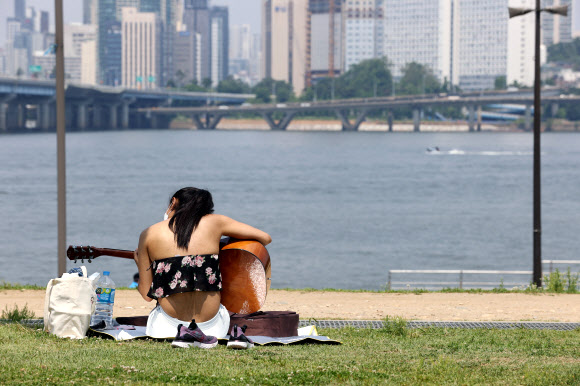 초여름 날씨를 보인 6일 오후 서울 여의도 한강공원에서 한 외국인이 기타를 치고 있다. 2021.6.6  연합뉴스