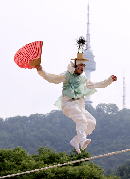 남산국악당 주최로 14일 오후 서울 중구 남산골한옥마을에서 열린 ‘라이브(LIVE) 남산’ 행사에서 줄타기 명인 남창동 씨가 공연을 펼치며 점프하고 있다.  라이브 남산은 포스트 코로나 시대의 다양한 관객 경험을 수용하기 위해 온오프라인 통합 콘텐츠 공연으로 기획됐다. 한옥마을 야외 공간에 30명 이내의 예약 관객을 받고 온라인 플랫폼을 통해서도 공연을 생중계한다. 2021.6.14  연합뉴스