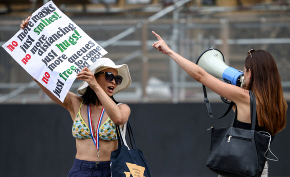 14일(현지시간) 영국 런던 국회의사당 광장에서 코로나19 봉쇄 해제 연기와 백신 접종에 항의하는 시위대가 플래카드를 들고 집회를 벌이고 있다. 로이터 연합뉴스
