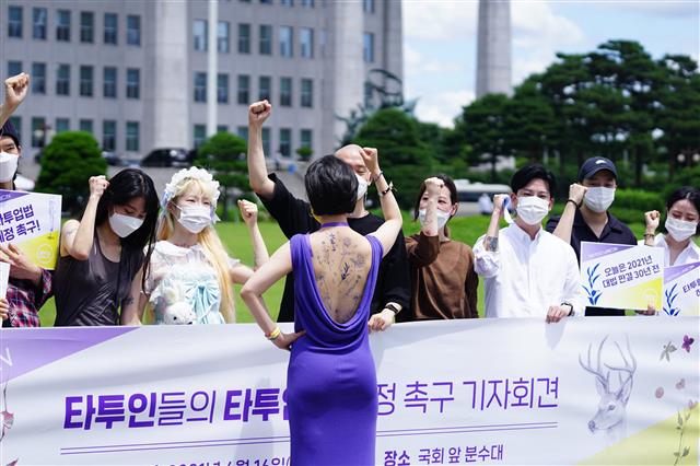 류호정 정의당 의원이 16일 서울 여의도 국회 본관 앞에서 열린 ‘타투업법 제정 촉구 기자회견’에서 타투가 그려진 등이 노출된 보라색 드레스를 입은 채 구호를 외치고 있다. 류 의원은 ‘K-타투’ 산업 육성과 타투이스트 노동권 보호를 위해 지난 6월 11일 ‘타투업법’을 대표 발의했다. 2021.6.16 류호정 의원 페이스북 캡처