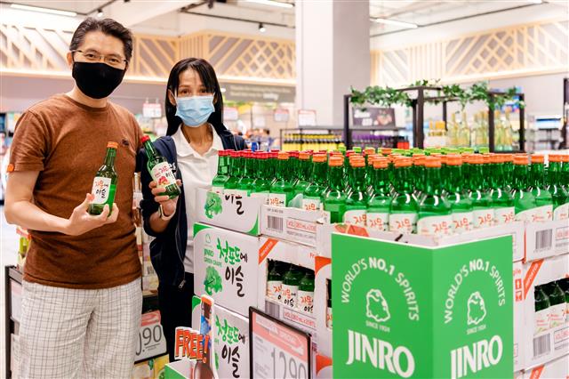 싱가포르 현지 소비자들이 한 마트에서 하이트진로의 과일리큐르(과일소주) 제품인 ‘자몽에이슬’(왼쪽)과 ‘자두에이슬’을 들고 포즈를 취하고 있다. 하이트진로 제공