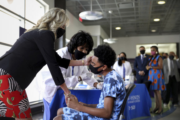 미국 영부인 질 바이든(왼쪽) 여사가 22일(현지시간) 미시시피주 잭슨주립대학에서 코로나19 예방접종을 받으며 긴장한 환자의 손을 잡아 주고 있다. AP 연합뉴스