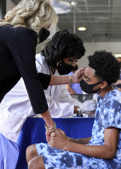 미국 영부인 질 바이든(왼쪽) 여사가 22일(현지시간) 미시시피주 잭슨주립대학에서 코로나19 예방접종을 받으며 긴장한 환자의 손을 잡아 주고 있다. AP 연합뉴스