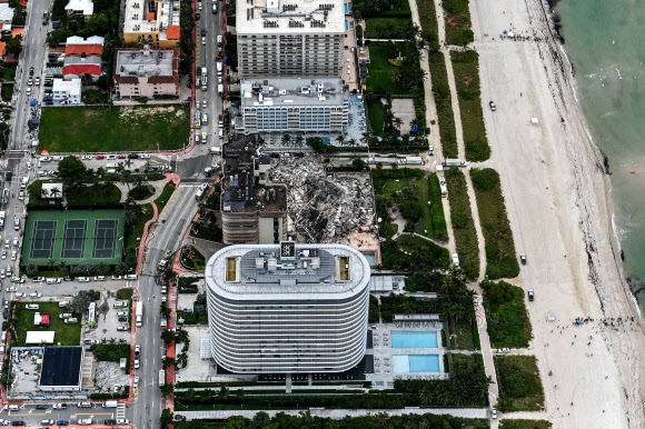This aerial view, shows search and rescue personnel working on site after the partial collapse of the Champlain Towers South in Surfside, north of Miami Beach, on June 24, 2021. - The multi-story apartment block in Florida partially collapsed early June 24, sparking a major emergency response. Surfside Mayor Charles Burkett told NBC?s Today show: ?My police chief has told me that we transported two people to the hospital this morning at least and one has died. We treated ten people on the site.? (Photo by CHANDAN KHANNA / AFP)/2021-06-25 07:01:53/ <연합뉴스