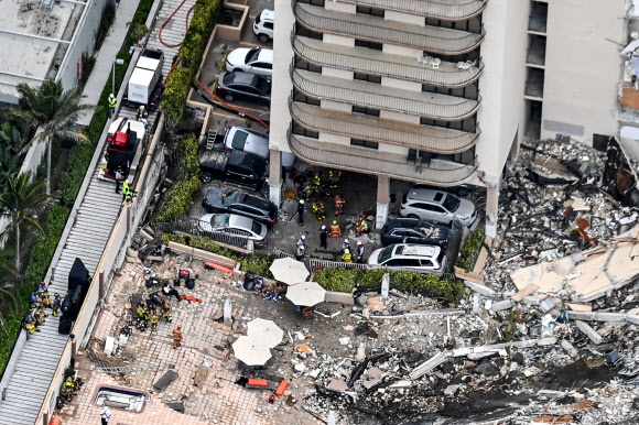 This aerial view, shows search and rescue personnel working on site after the partial collapse of the Champlain Towers South in Surfside, north of Miami Beach, on June 24, 2021. - The multi-story apartment block in Florida partially collapsed early June 24, sparking a major emergency response. Surfside Mayor Charles Burkett told NBC?s Today show: ?My police chief has told me that we transported two people to the hospital this morning at least and one has died. We treated ten people on the site.? (Photo by CHANDAN KHANNA / AFP)/2021-06-25 06:08:25/ <연합뉴스