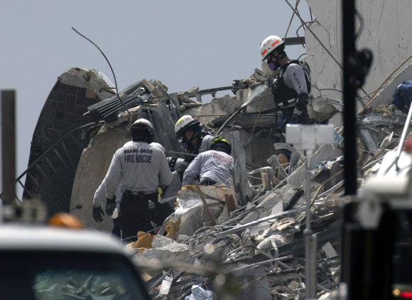 마이애미 데이트 소방 구조대원들이 25일(현지시간) 미국 플로리다주 서프사이드에서 발생한 12층 아파트 붕괴 현장에서 건물 잔해를 헤치며 생존자를 찾고 있다. 게티/AFP 연합뉴스