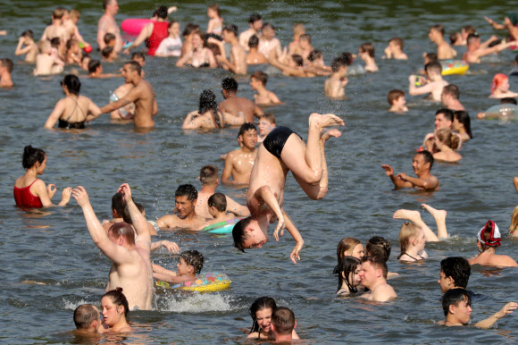 사람들은 26일(현지시간) 러시아 모스크바의 소콜니키 공원 연못에서 더위를 식히고 있다. 러시아 수도와 주변 지역은 낮 기온이 섭씨 30도를 넘으면서 덥고 맑은 날씨를 보이고 있다., 26일 모스크바의 낮 기온은 32도에 달했다. 타스 연합뉴스