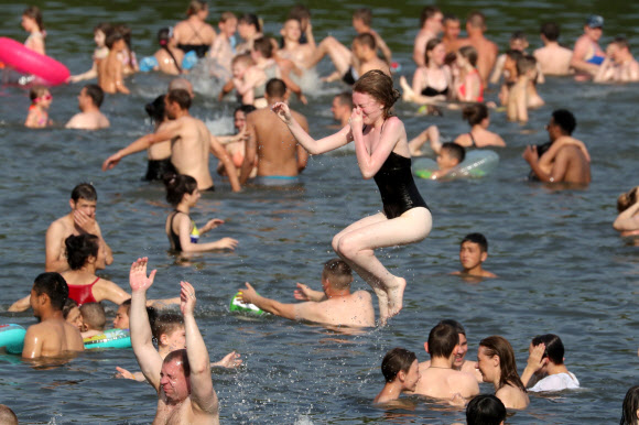 사람들은 26일(현지시간) 러시아 모스크바의 소콜니키 공원 연못에서 더위를 식히고 있다. 러시아 수도와 주변 지역은 낮 기온이 섭씨 30도를 넘으면서 덥고 맑은 날씨를 보이고 있다., 26일 모스크바의 낮 기온은 32도에 달했다. 타스 연합뉴스