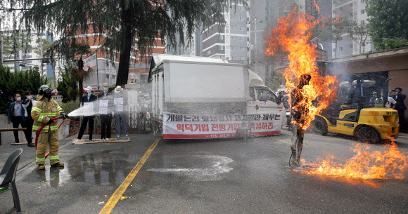 28일 오전 광주 북구 임동 옛 전남방직 공장에서 세입자들이 강제집행을 거부하며 마네킹에 불을 지르는 ‘화형식’ 퍼포먼스를 하자 소방관이 불을 끄고 있다. 2021.6.28  연합뉴스