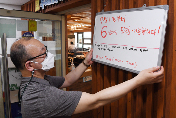 7월 1일부터 새로운 사회적 거리두기 개편안 시행을 하루 앞둔 30일 서울시내 한 음식점에서 점주가 6인이하 모임 가능 관련 안내문을 붙이고 있다. 2021.6.30 오장환 기자 5zzang@seoul.co.kr