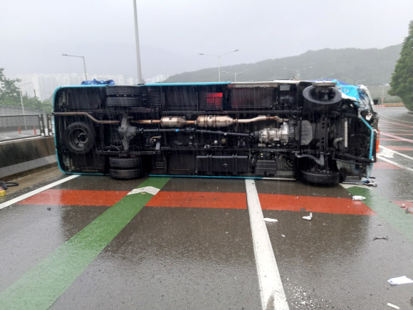 비가 내린 4일 오전 부산 도시고속도로 번영로 구서IC 인근을 달리던 통근버스가 넘어져 있다. 이 사고로 운전자인 70대 남성이 크게 다쳐 병원으로 옮겨졌고, 승객인 40대 남성 1명이 경상을 입었다. 2021.7.4  부산경찰청 제공