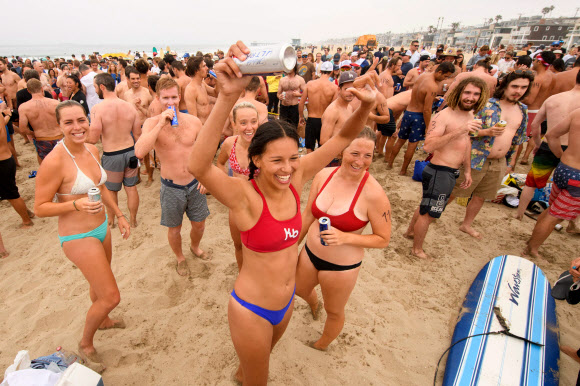 제47회 헤르모사비치 철인대회의 참가자들이 4일(현지시간) 미국 캘리포니아 헤르모사비치에서 1마일을 달리고, 1마일을 노를 젓고, 맥주 6팩을 마셔야 하는 경기에서 맥주를 마시고 있다. 40년 넘게 열린 이 비정규 3종 경기는 지난해 코로나19 대유행으로 취소된 뒤, 4일 재개됐다. 경쟁자들은 1마일을 달리고, 1마일을 서핑보드를 노를 젓고, 맥주 6팩을 마셔야 한다. 맥주를 토하는 사람들은 실격되지만, 누가 가장 잘 토하는가를 경쟁하는 사람들도 있다. AFP 연합뉴스