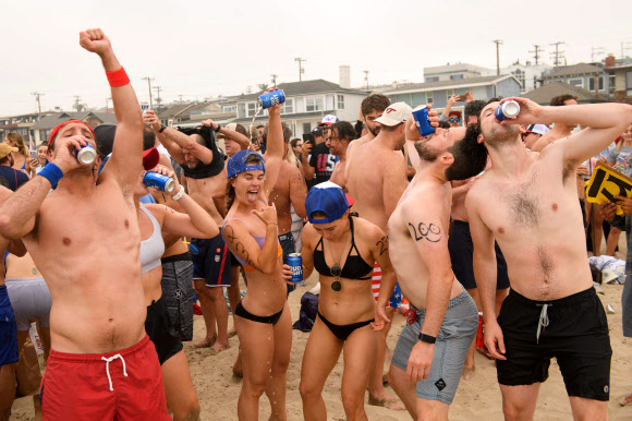 제47회 헤르모사비치 철인대회의 참가자들이 4일(현지시간) 미국 캘리포니아 헤르모사비치에서 1마일을 달리고, 1마일을 노를 젓고, 맥주 6팩을 마셔야 하는 경기에서 맥주를 마시고 있다. 40년 넘게 열린 이 비정규 3종 경기는 지난해 코로나19 대유행으로 취소된 뒤, 4일 재개됐다. 경쟁자들은 1마일을 달리고, 1마일을 서핑보드를 노를 젓고, 맥주 6팩을 마셔야 한다. 맥주를 토하는 사람들은 실격되지만, 누가 가장 잘 토하는가를 경쟁하는 사람들도 있다. AFP 연합뉴스