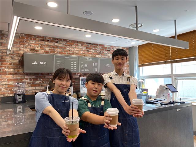 장애인 근로자 2명과 비장애인 카페 매니저가 5일 카페누리에서 제조한 음료를 선보이고 있다. JW그룹 제공