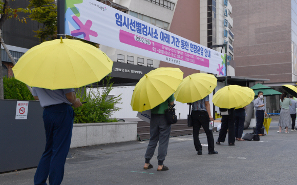 무더위가 기승을 부린 15일 서울 서초구 반포고속터미널에 마련된 임시 선별진료소를 찾은 시민들이 구청에서 마련한 우산을 쓴채 코로나 검사를 기다리고 있다. 2021.7.15 박지환기자 popocar@seoul.co.kr