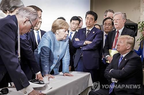 앙겔라 메르켈 독일 총리가 지난 2018년 6월 주요 7개국(G7) 정상회의 도중 탁자를 두 손으로 짚은 채 도널드 트럼프 당시 미국 대통령에게 결단을 압박하는 듯한 동작을 취하자 트럼프 대통령이 팔짱을 낀 채 쳐다보고 있다. AP 자료사진 연합뉴스 