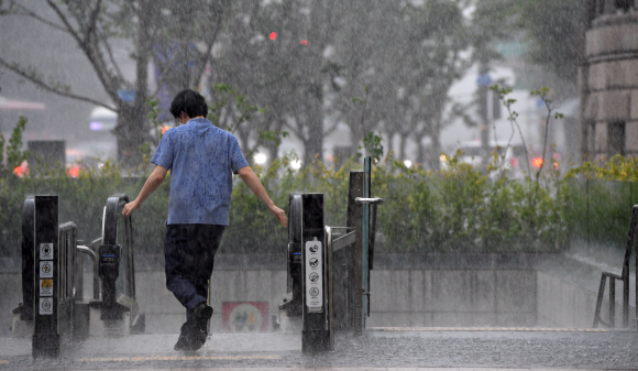 무더운 날씨를 보인 19일 서울 도서관 앞에서 갑자기 내린 소나기에  한 시민이 비를 피하고 있다. 2021.7.19 오장환 기자 5zzang@seoul.co.kr