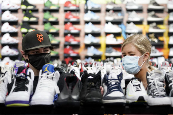 19일(현지시간) 미국 로스앤젤레스(LA)의 한 신발가게에서 고객들이 마스크를 쓴 채 쇼핑을 하고 있다. LA는 최근 코로나19 확진자 급증으로 실내 마스크 착용 의무화를 재도입했다. AP