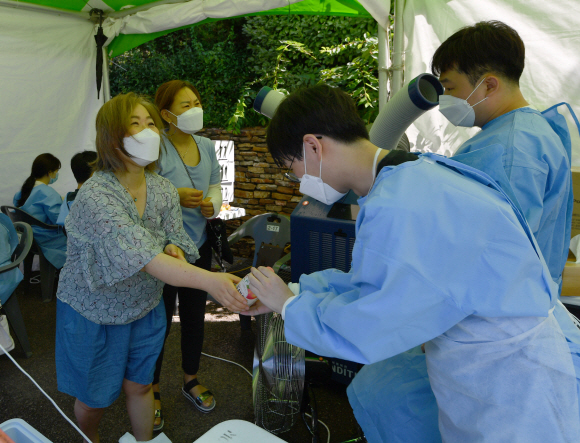 20일 서울 양천구 목동 파리공원에 마련된 임시선별진료소를 찾은 시민이 의료진에게 음료수를 건내고 있다.  2021.7.20 박지환기자 popocar@seoul.co.kr