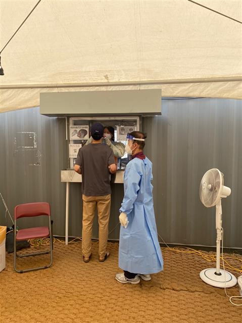 서울 용산역 코로나19 임시선별검사소에서 의료진과 행정요원이 선풍기 한 대에 의지해 코로나19 검사를 진행하고 있다.